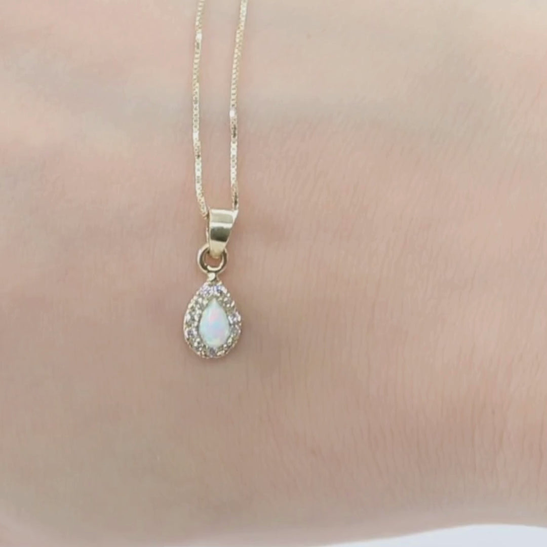 A drop-shaped halo pendant with a white opal stone on a 14K gold chain.